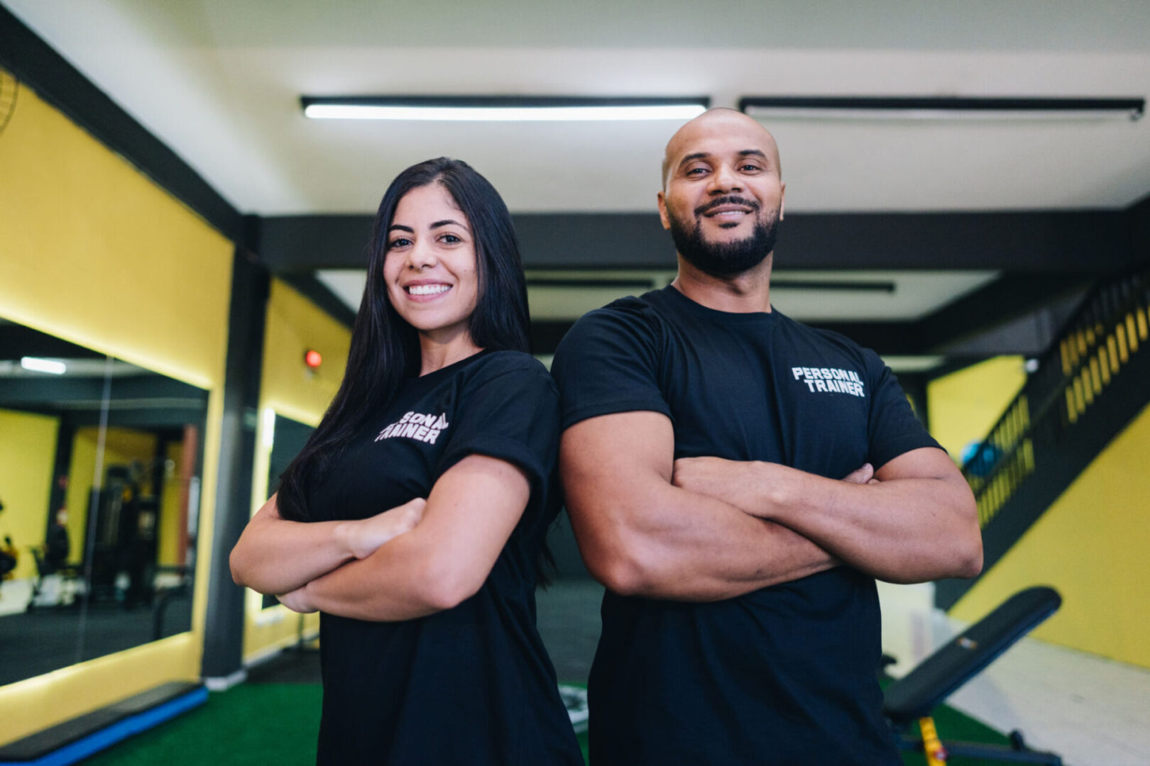 Two personal trainers smiling in a gym.